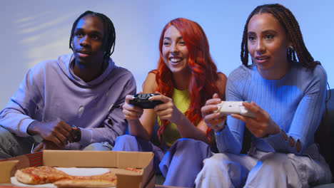 Group-Of-Gen-Z-Friends-Sitting-On-Sofa-At-Home-Gaming-And-Eating-Takeaway-Pizza